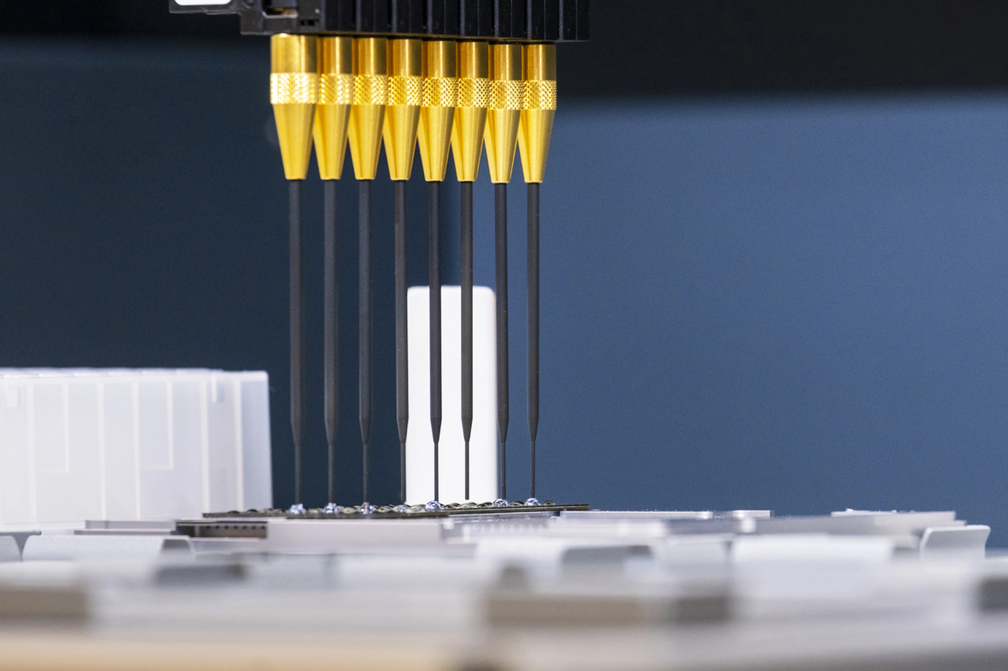 Close-up of golden pins with dark blue background in robotic system.